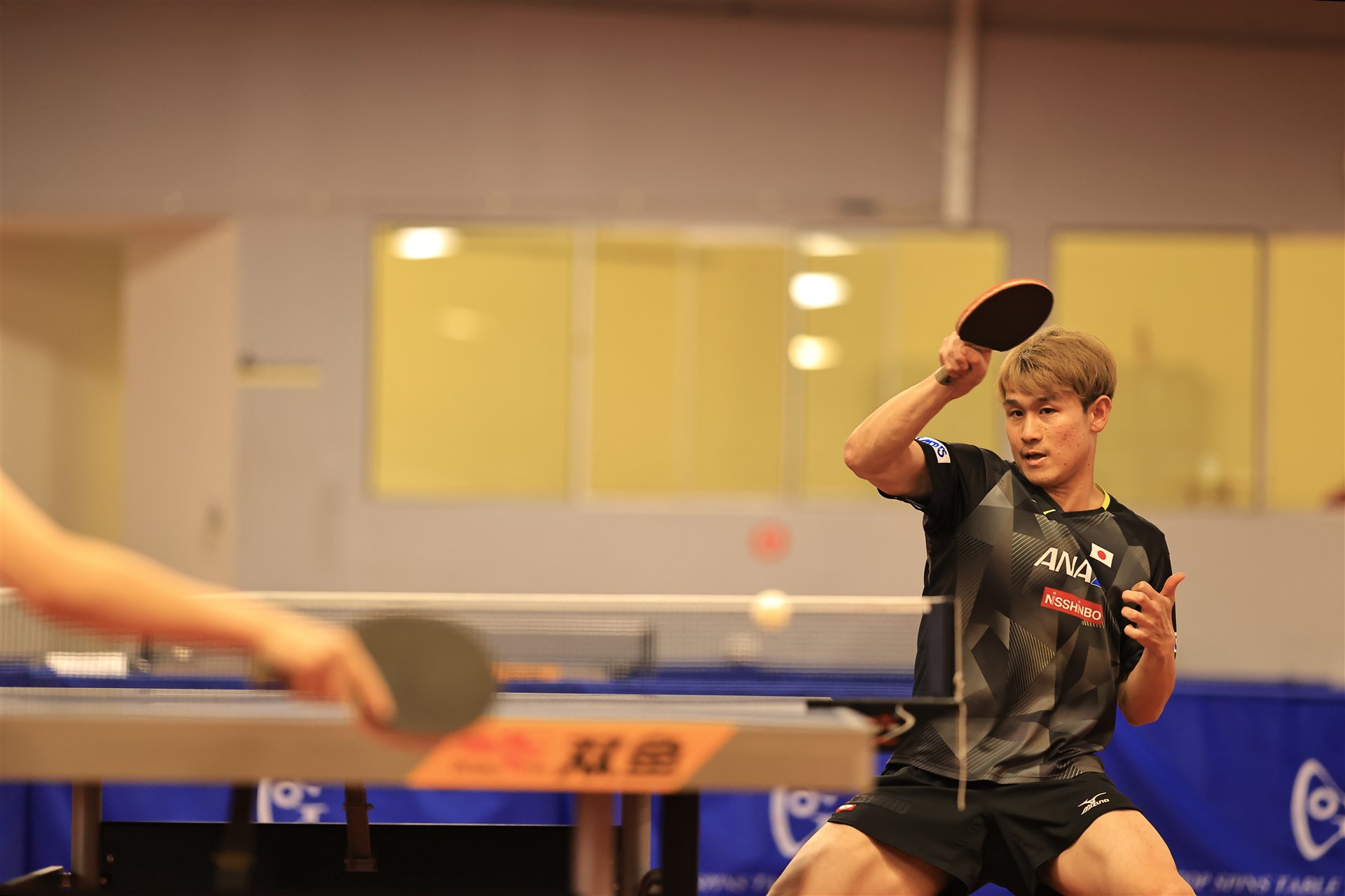 卓球台越しにラリーをする選手の試合写真